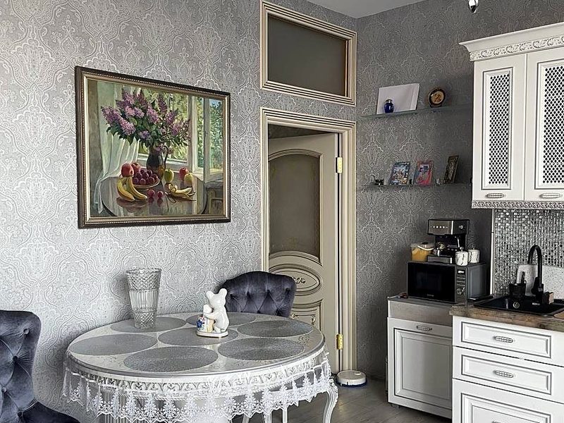 Кухня-гостиная в ЖК Level Донской: круглый стол на резной ножке, белая кухня, хрустальная люстра